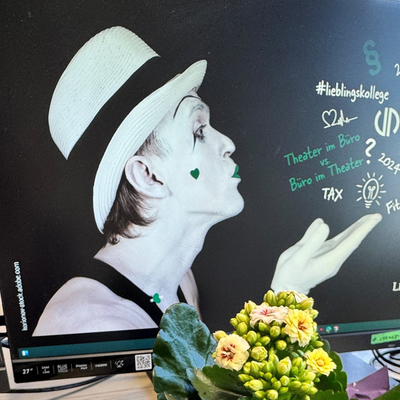 Ansicht eines Schreibtisches bei Lehleiter + Partner mit Bildschirmen, Tastatur und Blumen.