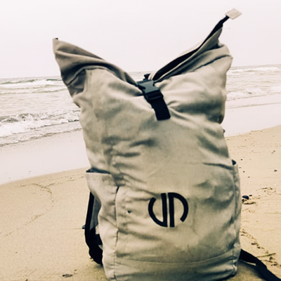 Ein grauer Rucksack mit Logo von Lehleiter + Partner am Strand mit dem Meer im Hintergrund.