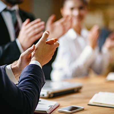 Businessmeeting mit applaudierenden Teilnehmern sitzend am Schreibtisch.